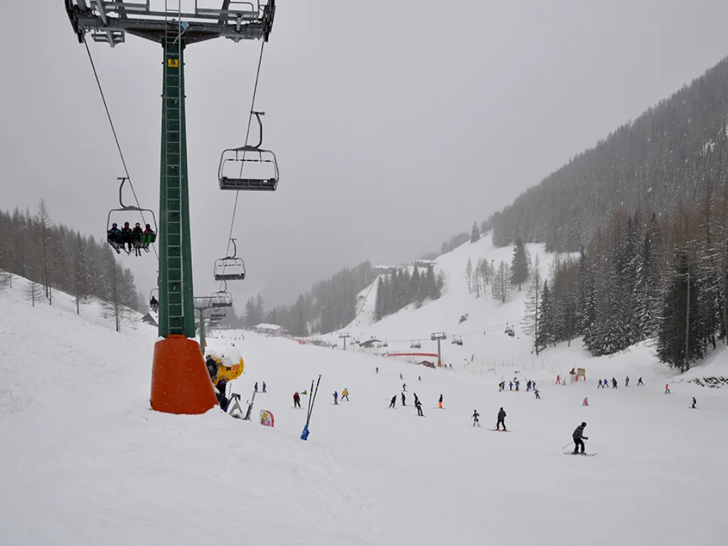 Sessellift über der Piste, unten sammeln sich viele Fahrende.